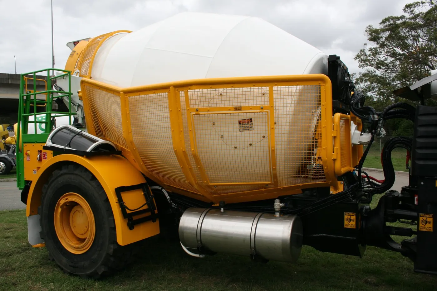 Full-length yellow mesh guarding along the side of the mixer barrel, with a stainless tank below