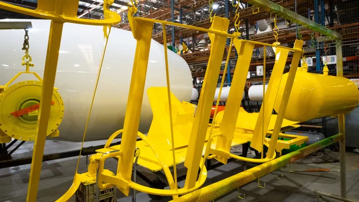 Mixer frames and components painted yellow, hanging in the paint line