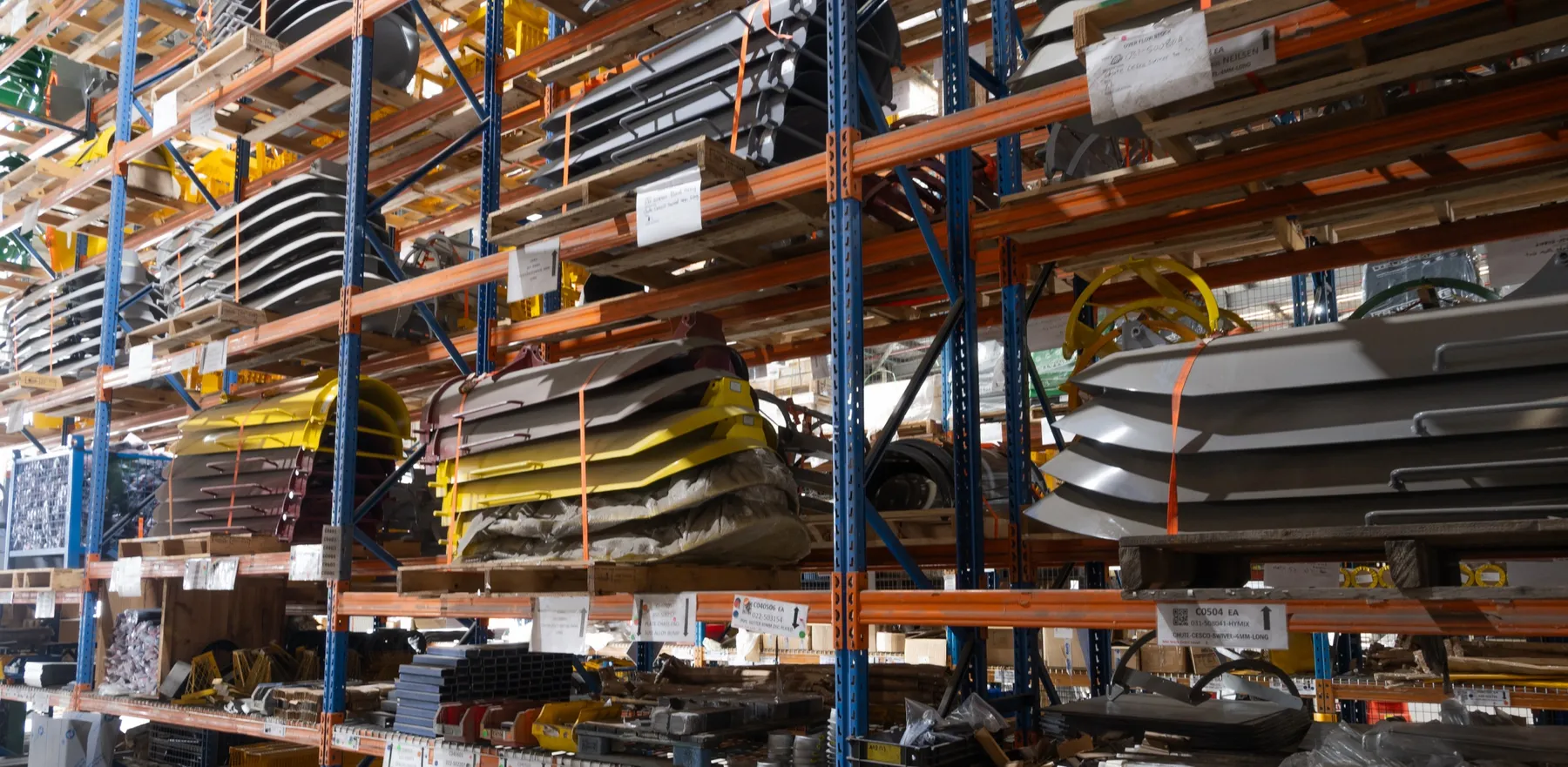 Stacked concrete mixer chutes and parts on racking in the Cesco parts store