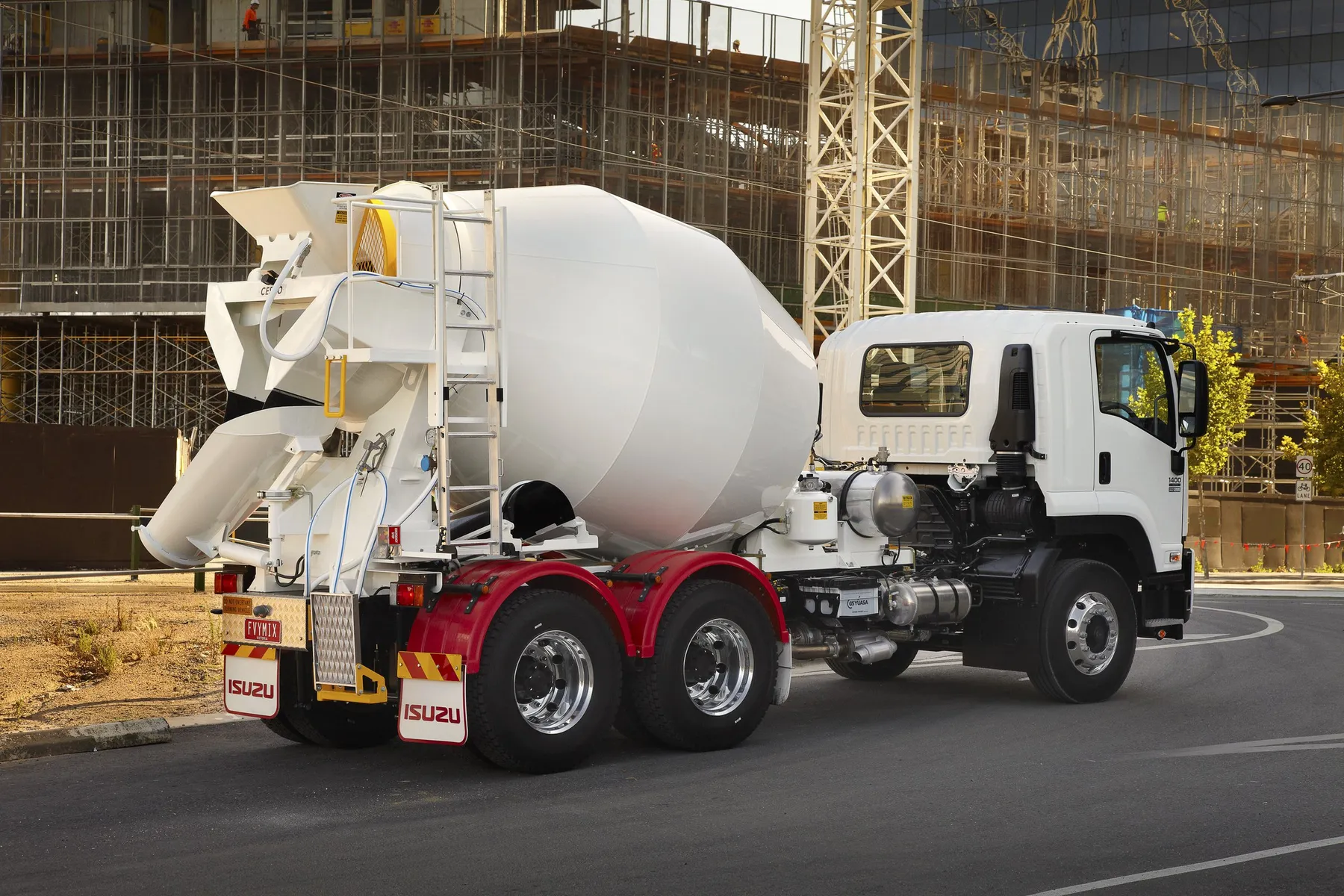 A white Cesco transit mixer on an Isuzu truck in front of a building under construction