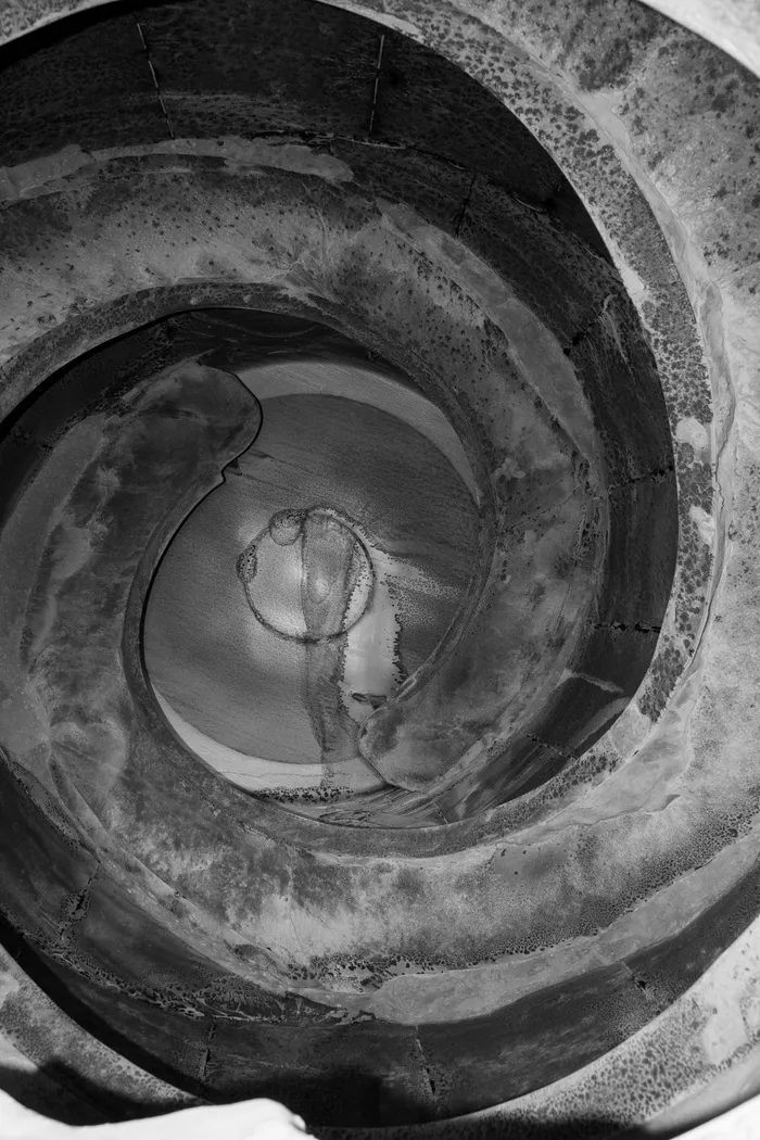 Worn blades inside a used concrete mixer barrel, coated in concrete residue