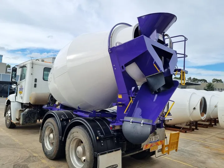 A refurbished mixer truck with a white barrel and purple chutes, back on the road